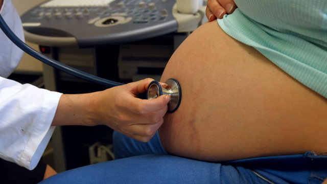 Doctor using a stethoscope on a pregnant womans stomach