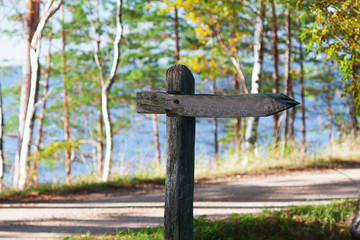Old wooden sign by the road and the sea