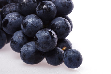 Fresh grape cluster on white with water drops