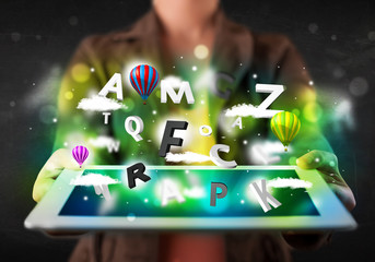 Young person showing tablet with abstract letters and sky