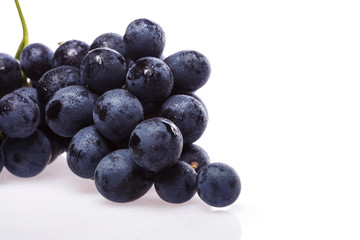 Fresh grape cluster on white with water drops