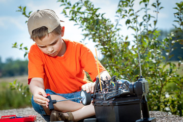 Little boy repaire the radio control car outdoor near field