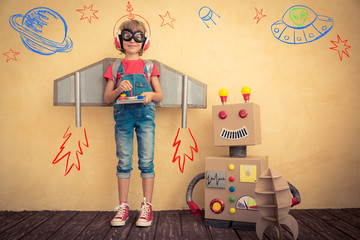 Happy kid playing with toy robot - obrazy, fototapety, plakaty