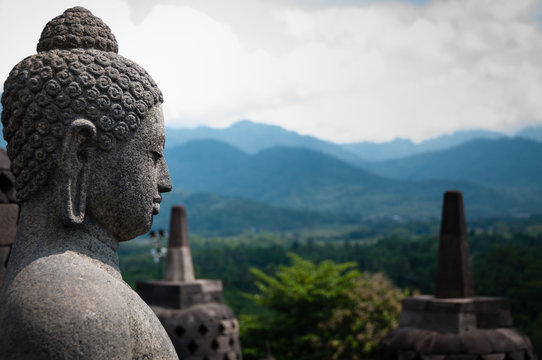 Stone budhha sideview in front of two stupas, Borobudur