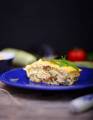Healthy zucchini lasagna bolognese on blue plate on wooden table