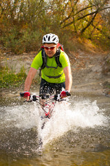 Young athlete crossing rocky terrain with bicycle in his hands