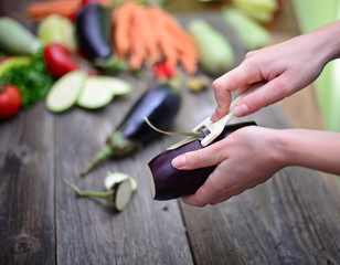 Woman's hand peeling fresh eggplant