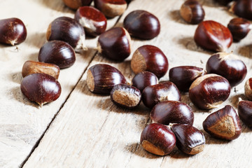Chestnuts on an old wooden table in the autumn background, selec