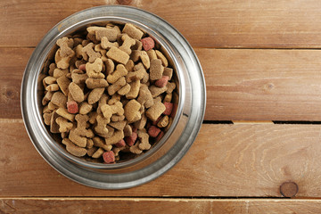 Dog food in bowl on wooden table