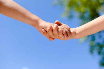 Closeup of two kid's hands holding each other in summertime