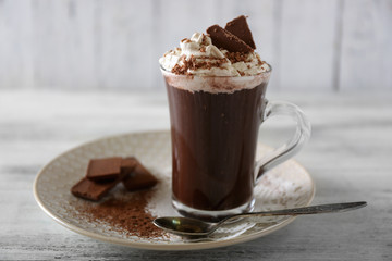 Cup of coffee with cream on color wooden background