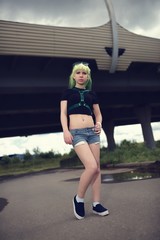 Obraz premium Beautiful young swag woman with green hair posing near highway road