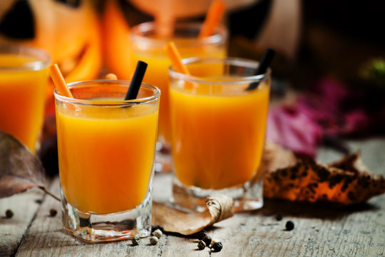 Fresh pumpkin juice on a dark Halloween background with burning