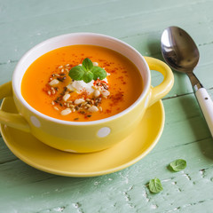 pumpkin soup in a yellow bowl on a wooden surface