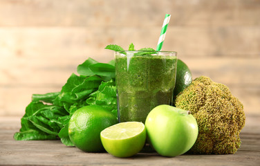 Green healthy juice with fruits and vegetables on wooden table close up