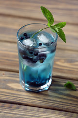 Glass of cold refreshing summer drink with berries and ice cubes on table close up