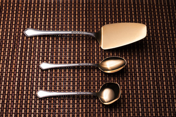 Silver kitchen utensils for dessert. Teaspoon, shovel cake and spoon for sugar on pattern table mat.