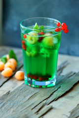 Glass of cold refreshing summer drink with berries and ice cubes on table close up