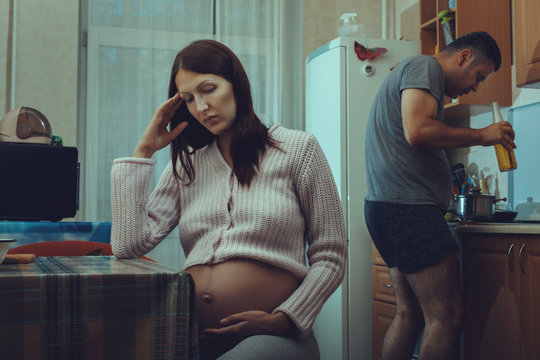  Pregnant woman sitting and sad,  her husband drinks alcohol.