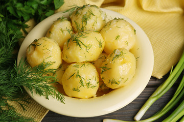 Boiled potatoes with greens in bowl on table close up