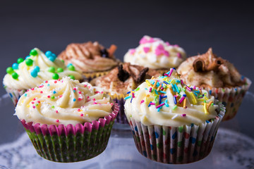 close up of sweet colorful cupcakes over gray