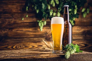 Selbstklebende Fototapete Bier Glas Bier und Flasche auf altem Holztisch und Holzbackgrou