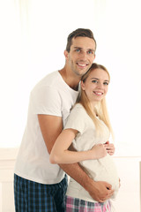 Young pregnant woman with husband in room