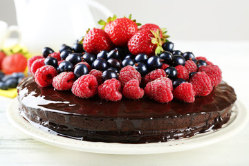 Delicious chocolate cake with summer berries on white wooden table, closeup