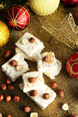 Sweet nougat with hazelnuts and Christmas decoration table close up