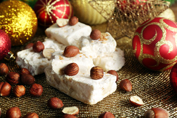 Fototapeta na wymiar Sweet nougat with hazelnuts and Christmas decoration table close up