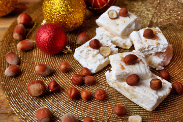 Sweet nougat with hazelnuts and Christmas decoration table close up