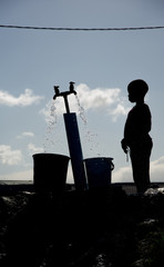 Silhouette of a young boy gathering water at a well in Langa, South Africa, a township located on...