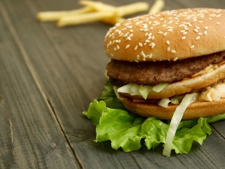 Hamburger and fries on a wooden cutting board