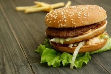 Hamburger and fries on a wooden cutting board