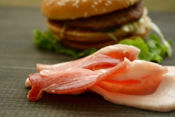 Hamburger and fresh bacon on a wooden cutting board
