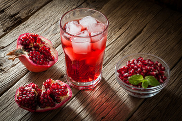 Pomegranate with and pomegranate juice on wooden background