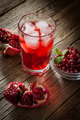 Pomegranate with and pomegranate juice on wooden background