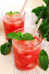 Cold watermelon pieces in glasses, on wooden table background