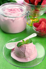 Watermelon ice cream in glass jar and on plate, on color wooden background