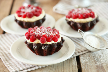 Sweet cakes with raspberries on light wooden background