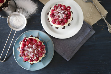 Sweet cakes with raspberries on color wooden background