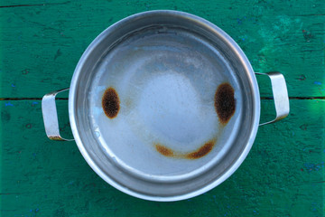 Food burnt in the form of a smiley. Pan of stainless steel with