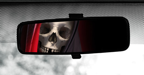 Rear view mirror reflecting Grim Reaper. Road safety theme.