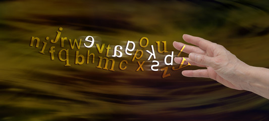Understanding Dyslexia Website Banner -  female hand with the alphabet flowing from fingers in gold with six letters flipped in white to symbolize dyslexia  - obrazy, fototapety, plakaty
