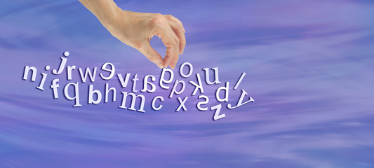 Pinpointing Dyslexia Website Banner -  female hand picking out a reversed G from a jumble of alphabet letters flowing across the  page symbolizing dyslexia  - obrazy, fototapety, plakaty