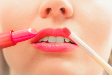Naklejka premium Woman applying lipstick with brush on lips. Makeup