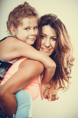 Fototapeta premium Mother parent giving kid piggyback ride.