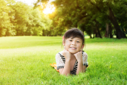 Little Asian Girl Laying Down On The Green Grass