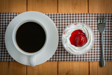 Coffee cup with strawberry cake on wooden table