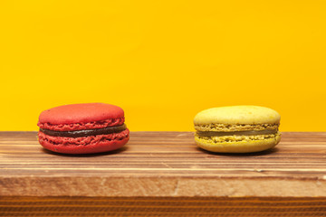 Pile of colorful macarons stacked up in the white classic cup in yellow pastel isolated background